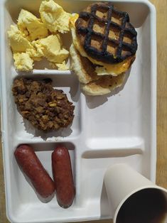 a white tray topped with breakfast foods and waffles on top of a wooden table