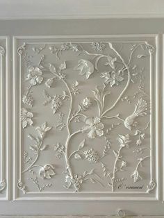 an intricately designed wall panel with flowers and leaves in white, painted on the ceiling