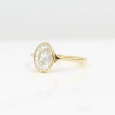 a yellow gold ring with a single diamond in the center, on a white surface