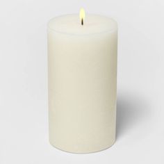 a white pillar candle with a single lit candle in the middle on a white background