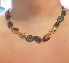 a woman wearing a multicolored necklace with leaves attached to it's neck