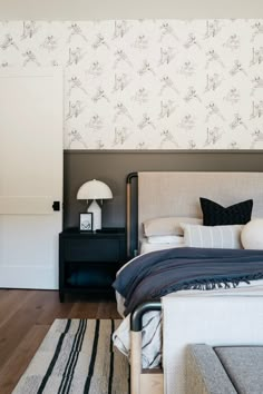 a bedroom with a bed, nightstand and wall paper