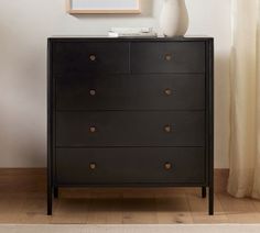 a white vase sitting on top of a black dresser