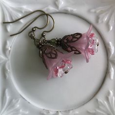 "Pretty in Pink... Add some spring to your wardrobe with these lovely double pink blossoms. Delicate pink petals surround bright pink and white centers. Antique brass filigree caps adorn the tops and a tiny green bead adds a bit of spring pop. These earrings are very lightweight and comfortable to wear. Perfect for a garden wedding, or a gift for a nature lover. And don't forget...Mother's Day is just around the corner. Drop length from bottom of antique brass french earwire: 1\" (25mm) Prefer a Pink Handmade Flower Earrings For Spring, Pink Petal-shaped Earrings For Spring, Pink Earrings With Handmade Flowers For Spring, Spring Pink Earrings With Flower Charm, Spring Pink Earrings With Handmade Flowers, Delicate Pink Flower Jewelry, Handmade Pink Feminine Earrings, Pink Feminine Flower Drop Earrings, Feminine Pink Jewelry With Handmade Flowers