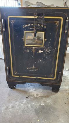 an old black and gold safe sitting on the ground