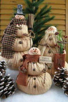 three snowmen are sitting next to pine cones