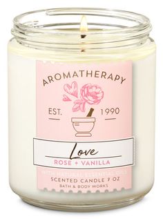 a white candle with pink flowers on the front and label that says aroma therapy love