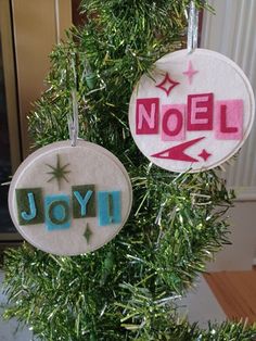 two ornaments hanging from a christmas tree with the words noel and joy written on them