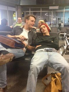 two men sitting on a bench in an airport