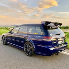 the blue car is parked on the side of the road with its roof rack up