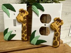 two giraffes are made out of white electrical outlet covers with green leaves on them