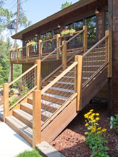 a wooden deck with railings and flower pots on the side of it next to a building