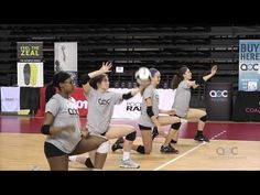 girls in grey shirts playing volleyball on a court with people watching from the sidelines