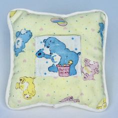 a yellow pillow with a blue bear and other stuffed animals on the front is shown