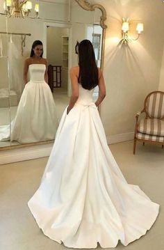 a woman standing in front of a mirror wearing a wedding dress