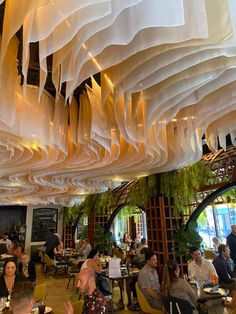 people sitting at tables in a restaurant with white paper hanging from the ceiling