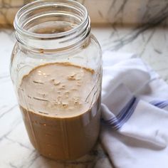 a jar filled with brown liquid sitting on top of a table next to a napkin