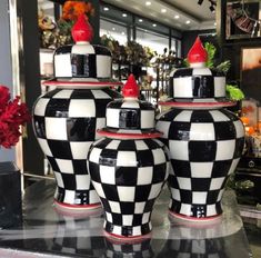 three black and white vases sitting on top of a counter in a store front