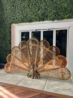 a bamboo fan sitting on top of a wooden floor next to a window covered in ivy