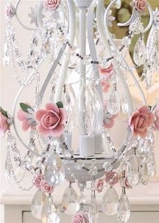 a white chandelier with pink roses and crystals hanging from it's sides