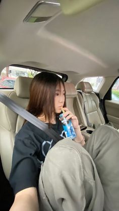 a young woman sitting in the back seat of a car drinking from a water bottle