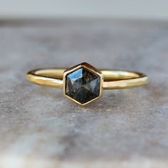 * Rose Cut Dark Gray Diamond in a Hexagon Shape, 6mm in diameter, 1 carat weight * 18k yellow gold setting and band * hammered band measures 1.6mm wide * Recycled gold and 100% conflict-free diamond * Model's finger is a size 6.5 * 2 Week Processing Time The large, rose cut natural color deep gray diamond at the center of this unique engagement ring is simply stunning. The hexagonal diamond is expertly faceted in a gorgeous step pattern for maximum sparkle and pop. The diamond is enveloped in a Masculine Engagement Rings, Hexagon Diamond Ring, Hexagon Engagement Ring, Hexagon Diamond, Hammered Band, Unique Engagement Ring, Natural Diamond Ring, Rose Engagement Ring, Yellow Gold Setting