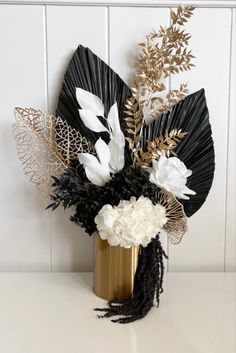 a vase filled with white and black flowers on top of a table next to a wall