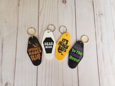 three keychains with different designs on them sitting on a white wooden surface,