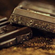 two pieces of chocolate sitting next to each other on top of a wooden table covered in dirt