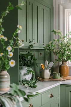 green painted kitchen cabinets with flowers in vases on the counter and utensils