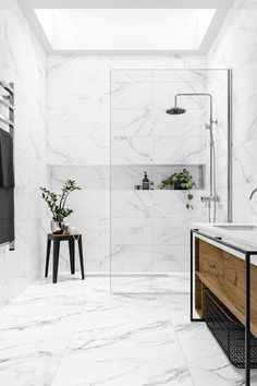 a bathroom with white marble walls and floor, along with a walk in shower area