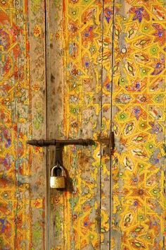 an open door with a lock on it and colorful wall paper behind it in the background