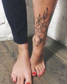 a woman's foot with a flower tattoo on her left leg and red nail polish