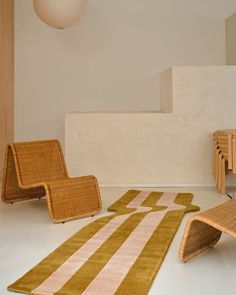 a living room with chairs and rugs on the floor in front of a stair case