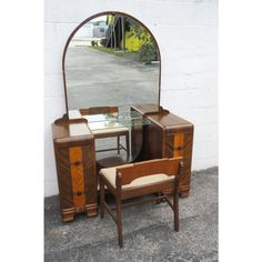 a dressing table with mirror and chair in front of a white brick wall on the street