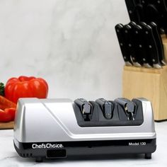 the chef's choice knife sharpener is next to several knives and peppers on a cutting board