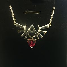 a necklace with a red stone in the shape of a bird on it's back