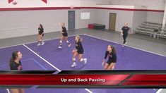 the girls are playing volleyball on the court in an indoor gym with purple flooring