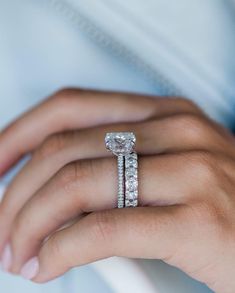 a woman's hand with a diamond ring on her finger and the other hand holding an engagement ring