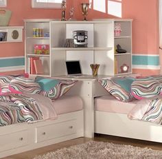 two twin beds in a room with pink walls and white bookcases next to each other