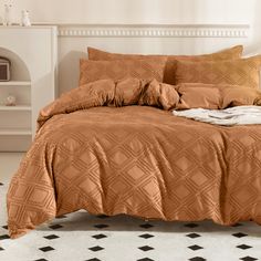 a bed with an orange comforter and pillows