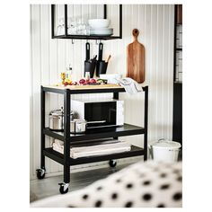 a kitchen cart with various items on it in front of a white wall and floor