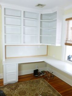 an empty room with white bookcases and wood flooring