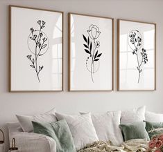 three black and white floral prints hanging on the wall above a couch in a living room