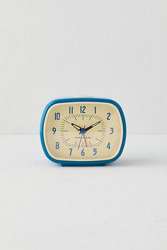 a small blue and white clock sitting on top of a table next to a wall