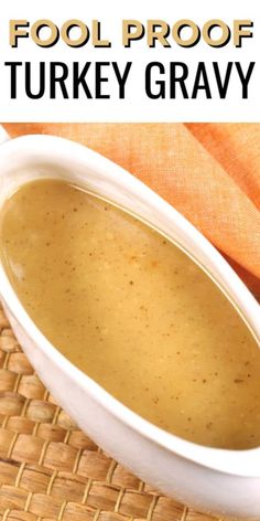 a white bowl filled with turkey gravy on top of a woven table cloth