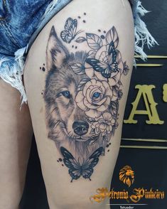 a woman's thigh with a wolf and flowers tattoo on it