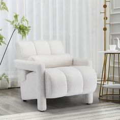 a white chair sitting on top of a hard wood floor next to a tall plant