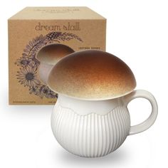 a white ceramic mushroom shaped mug next to a box