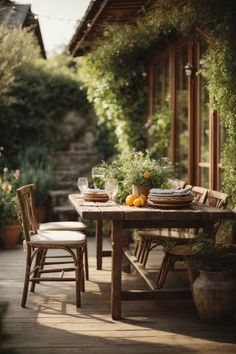 a wooden table with two chairs and plates on it in the middle of a patio